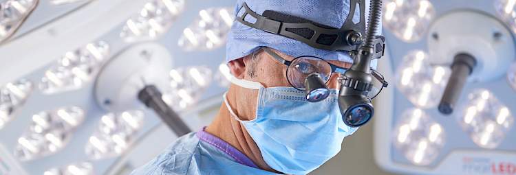 Chirurgien dans une salle d'opération qui opère avec des lunettes microscope