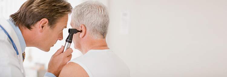Un médecin examine l'oreille un patient avec un otoscope