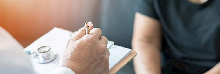 Un médecin est en entretien avec un patient et il prend des notes sur le traitement à prescrire